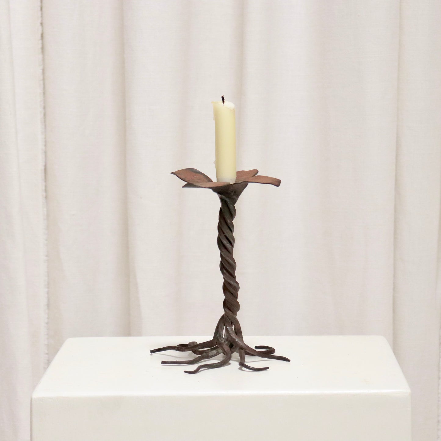 “Hand-forged iron candlestick with twisted stem and petal drip tray”