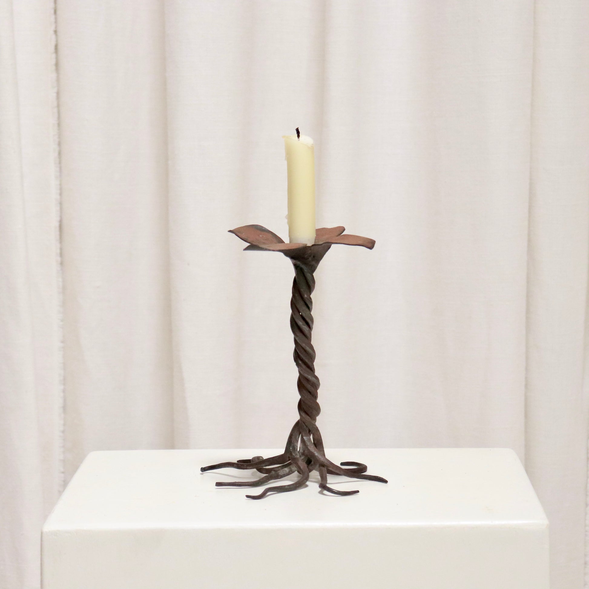 “Hand-forged iron candlestick with twisted stem and petal drip tray”