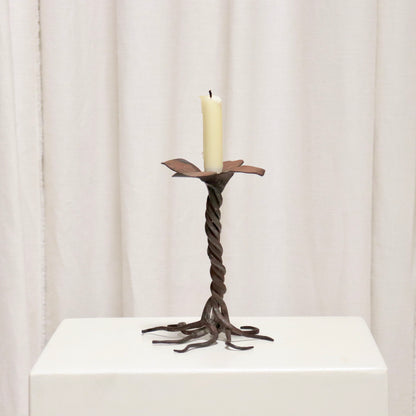 “Hand-forged iron candlestick with twisted stem and petal drip tray”