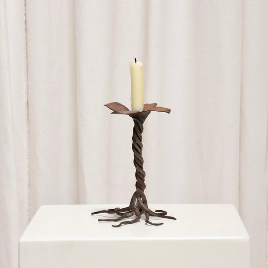 “Hand-forged iron candlestick with twisted stem and petal drip tray”