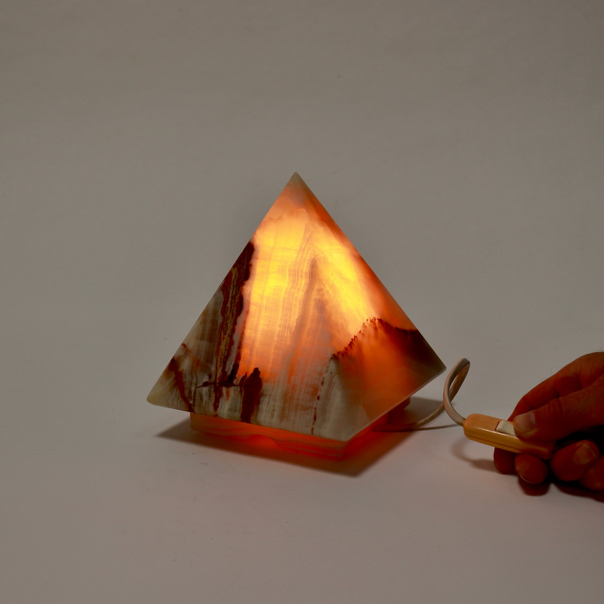 Illuminated onyx pyramid lamp glowing amber from within