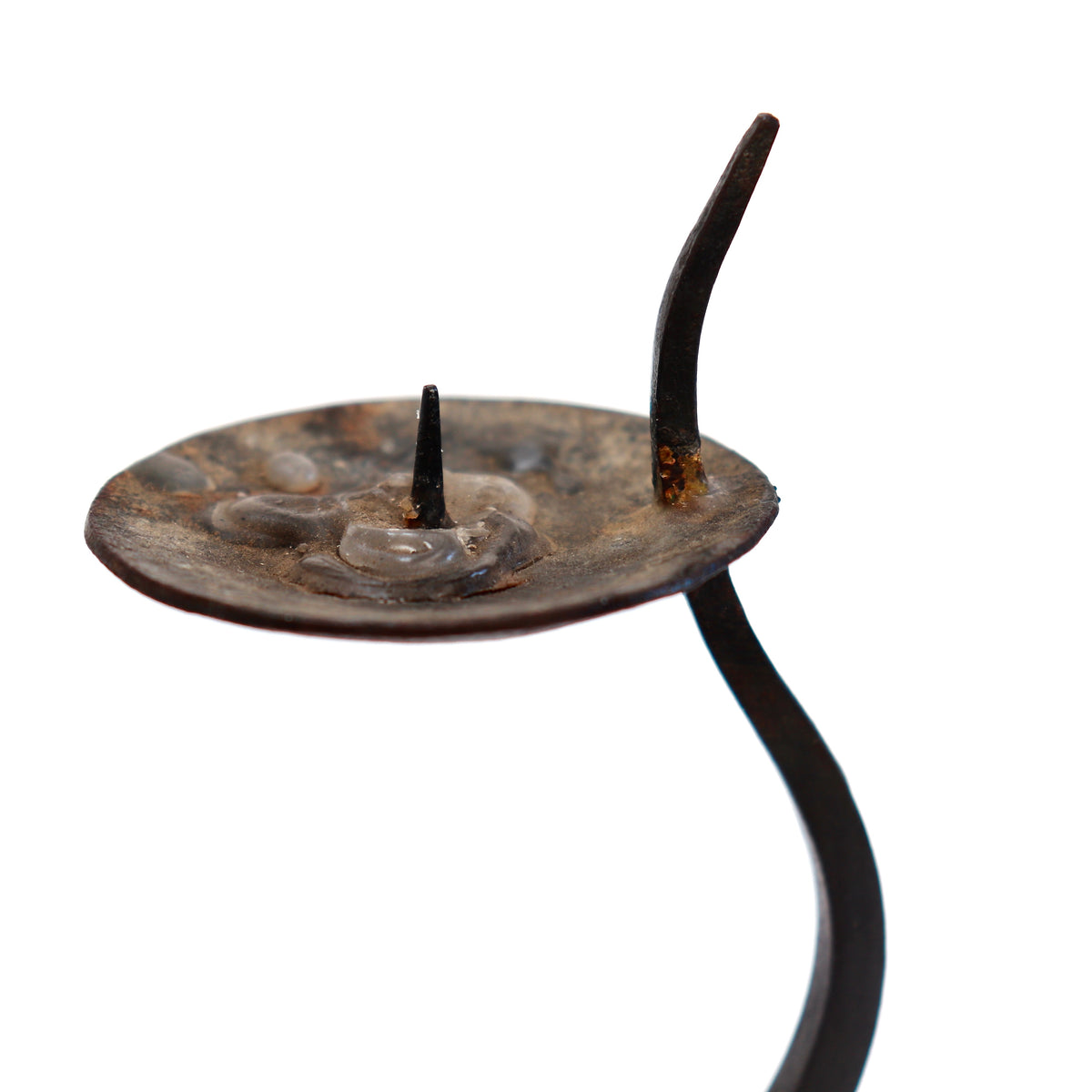 Detail of the shallow candle dish, white taper and pointed iron stem extending beside it.