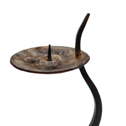 Detail of the shallow candle dish, white taper and pointed iron stem extending beside it.