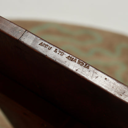 Impressed stamp reading ACCU LTD AMAWBIA on the edge of the hardwood tabletop.