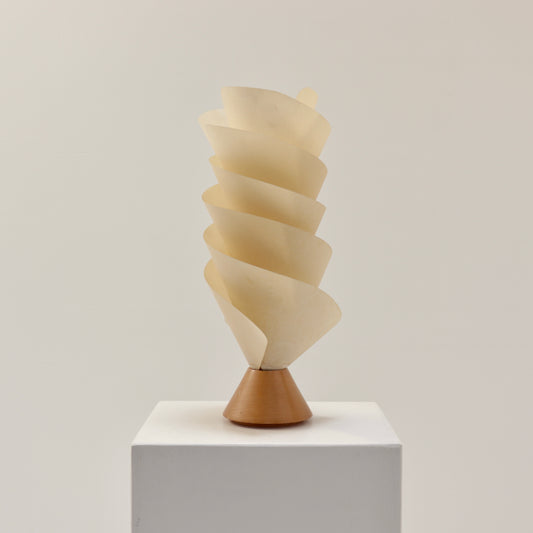 Postmodern spiral parchment table lamp with wooden base, 1980s design, sculptural lighting object on white plinth.