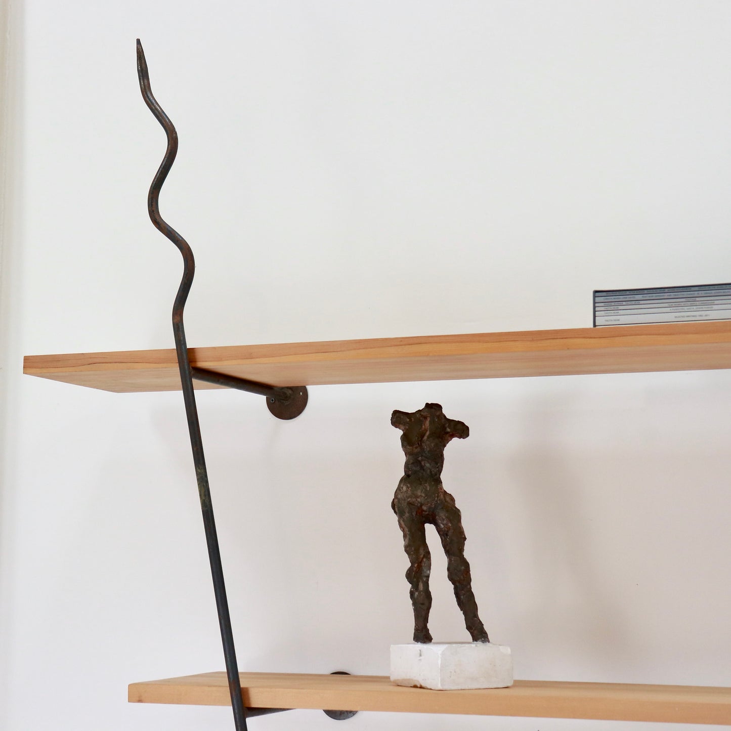 Close-up of upper shelf with serpentine forged-iron upright and bracket.