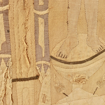 A close-up of a textured, distressed textile featuring beige and tan woven fabric with stitched details, frayed edges, and muted taupe accents.