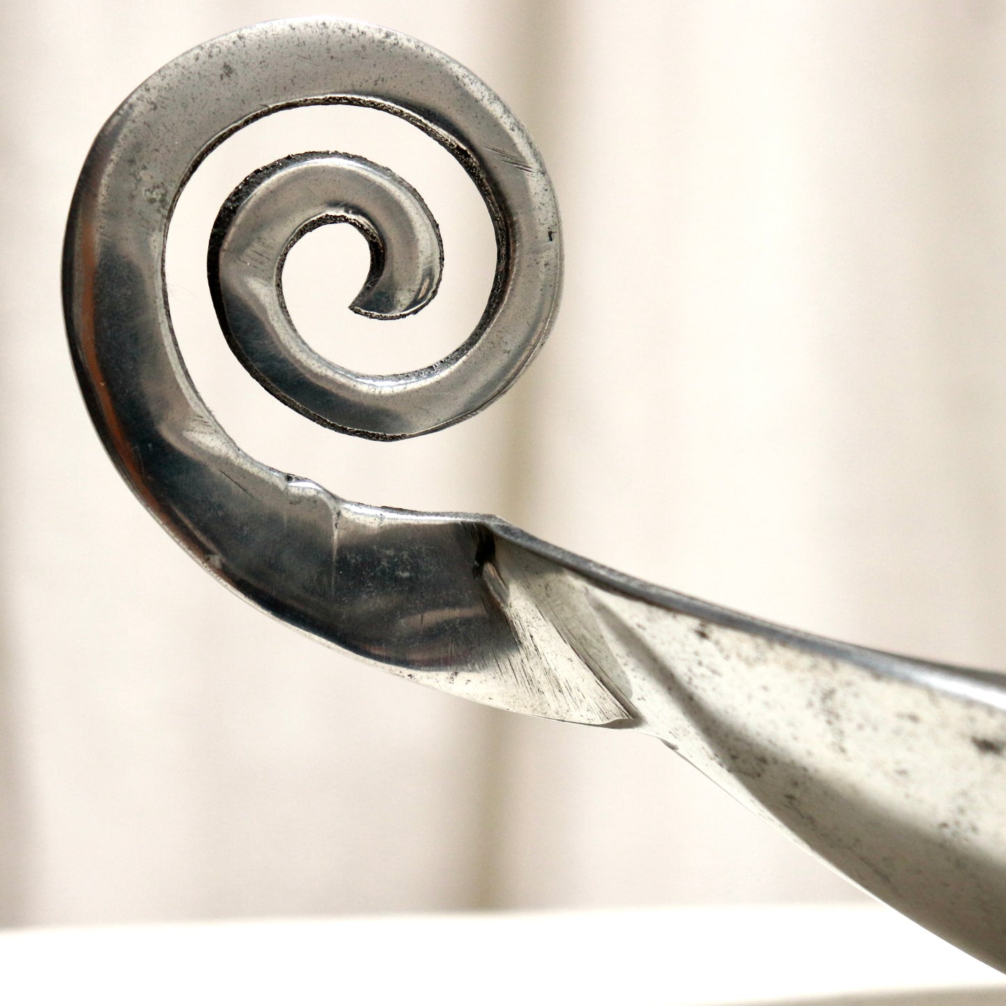 Close-up of scroll handle detail on aluminium dish.