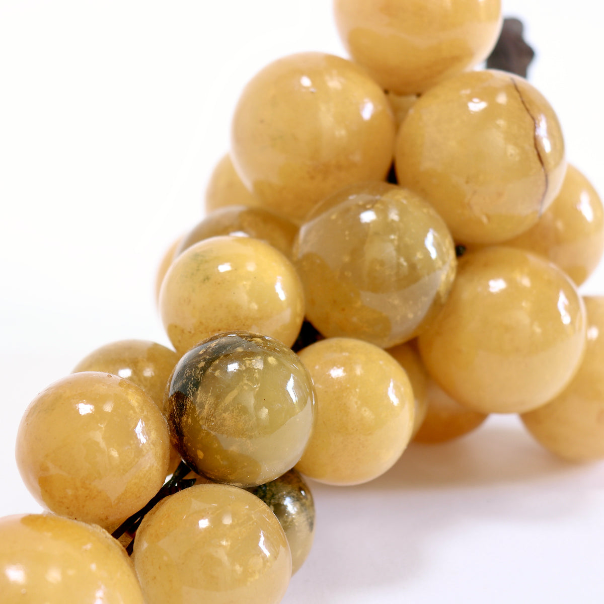 Close-up of golden and smoky brown alabaster grapes showing cloudy veining, surface wear and a crack or repair line.