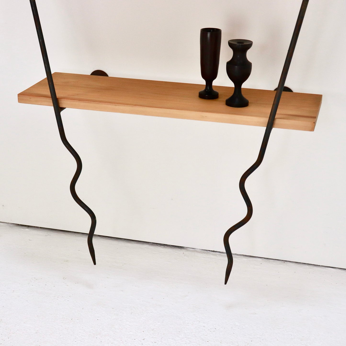 Lower timber shelf styled with dark wooden vessels on the wall system.