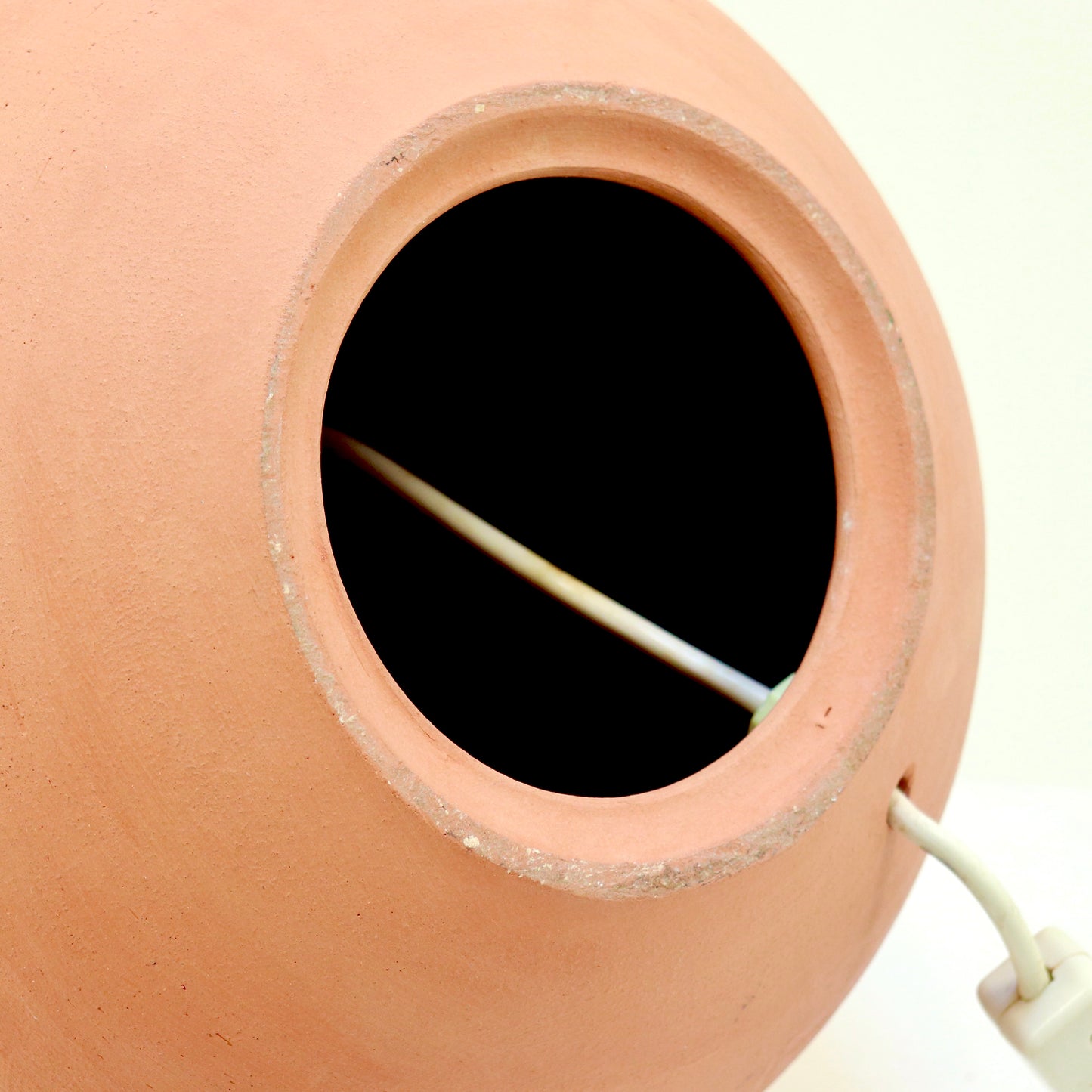 Underside of terracotta lamp showing cable entry