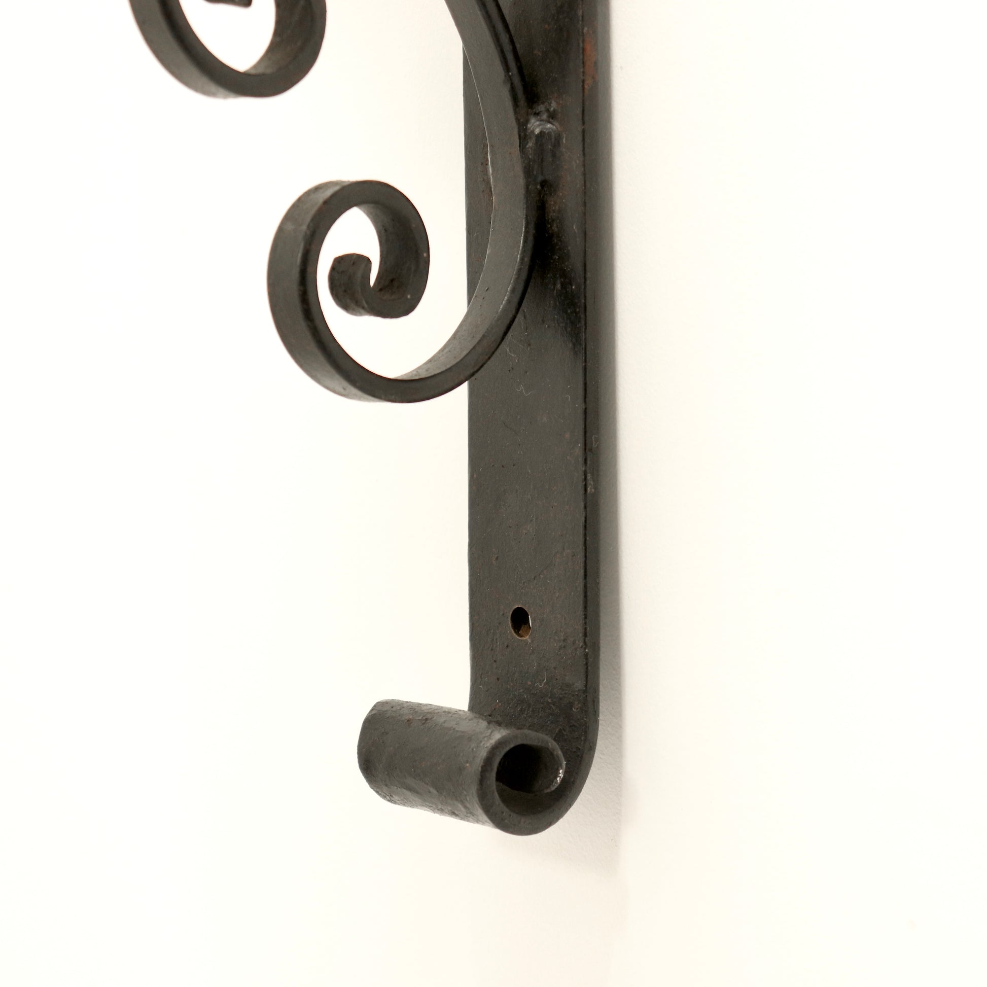 Close-up of wrought-iron scrollwork on the wall light backplate