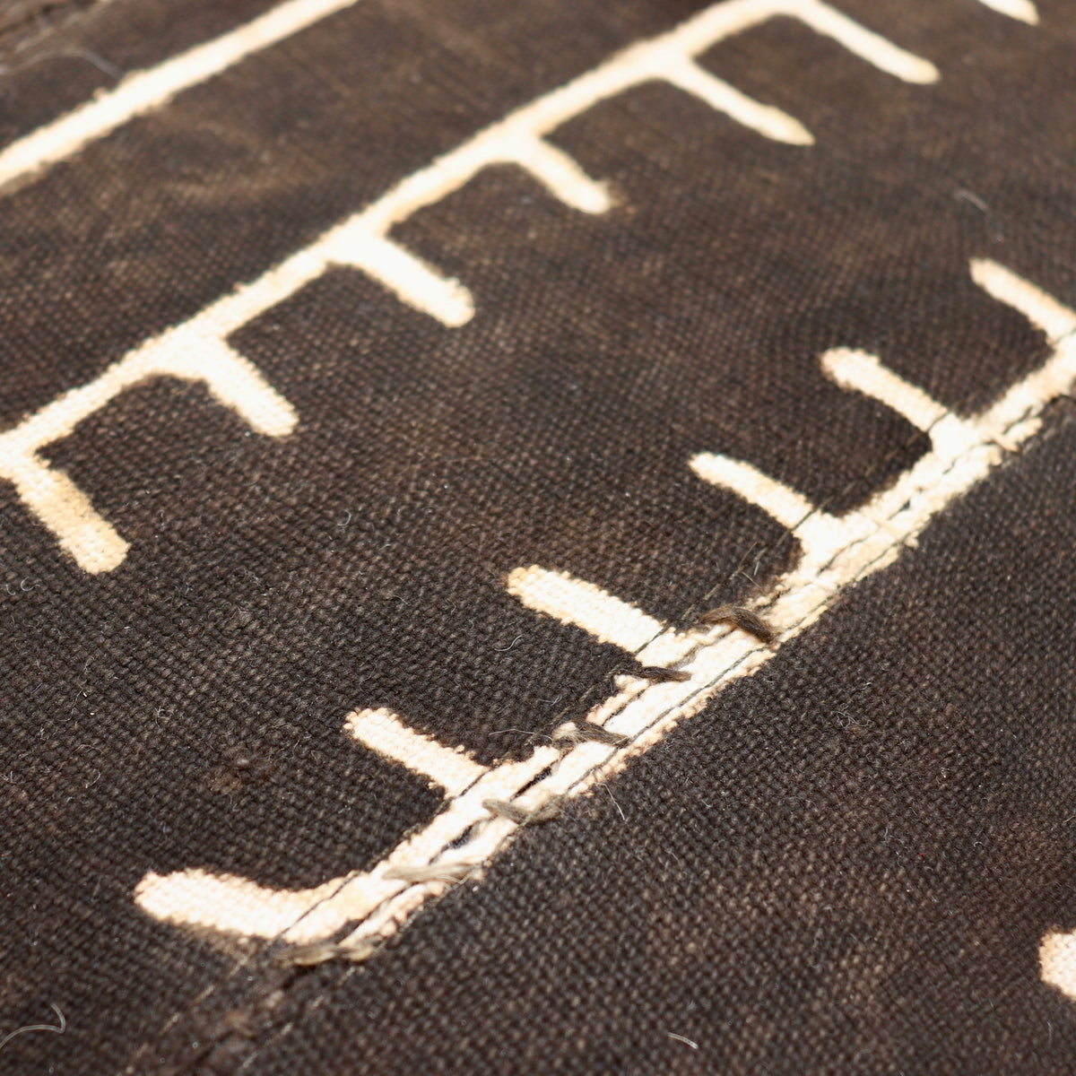 Close-up of mud cloth on a Heal’s armchair back, showing joined cotton strips, pale dots and a stepped geometric line.