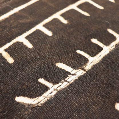 Close-up of mud cloth on a Heal’s armchair back, showing joined cotton strips, pale dots and a stepped geometric line.