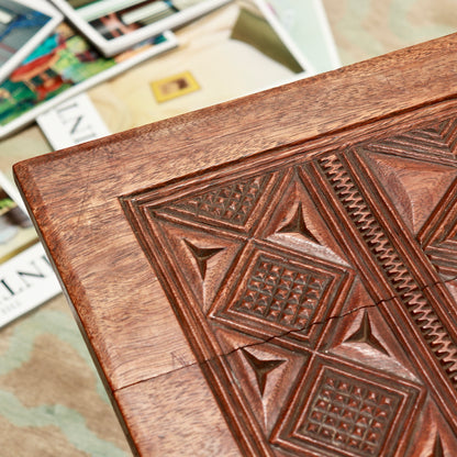 Detail of diamond and triangular chip carving on the tabletop, showing surface wear and a split along the grain.
