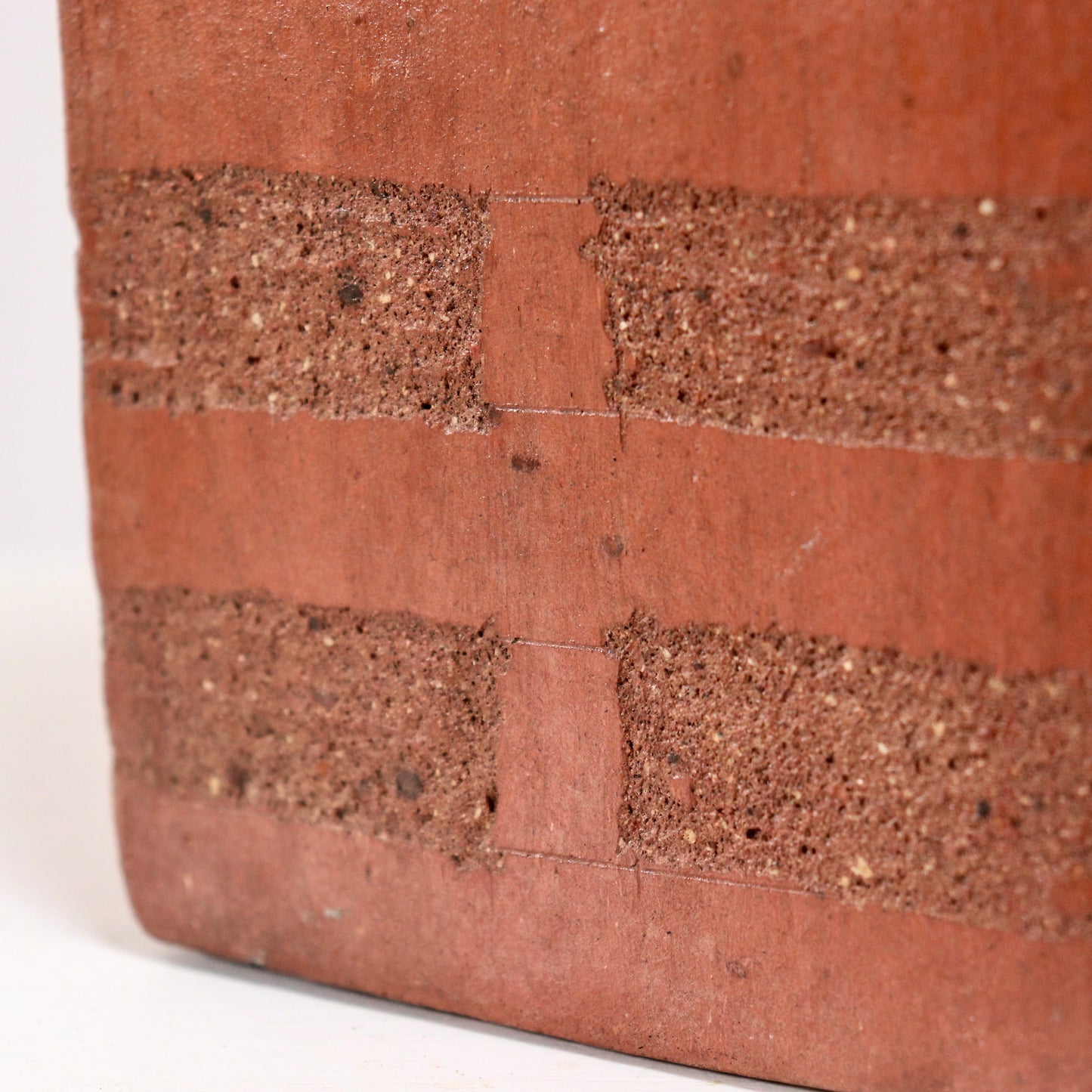 Angled macro of textured band and join line on hand-built terracotta vase.