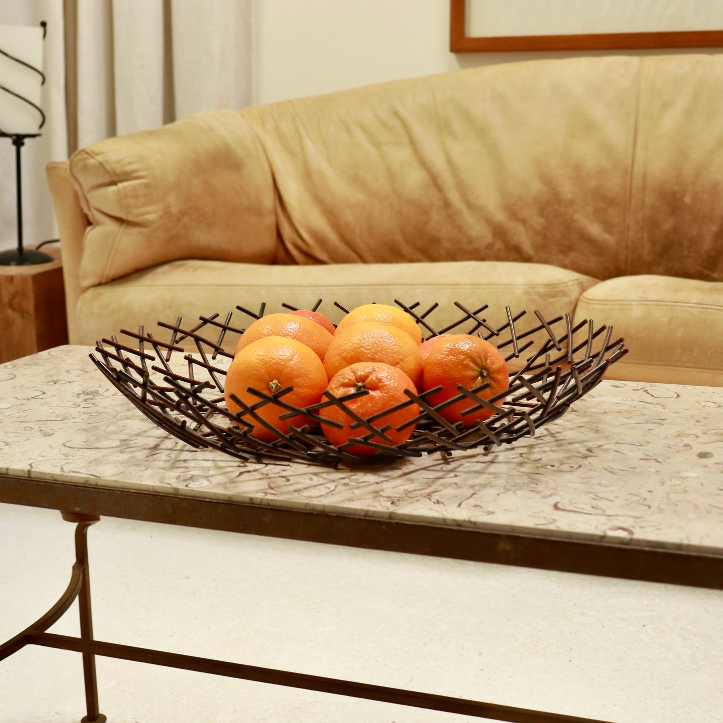 “Patinated metal fruit bowl with crossed rod construction”