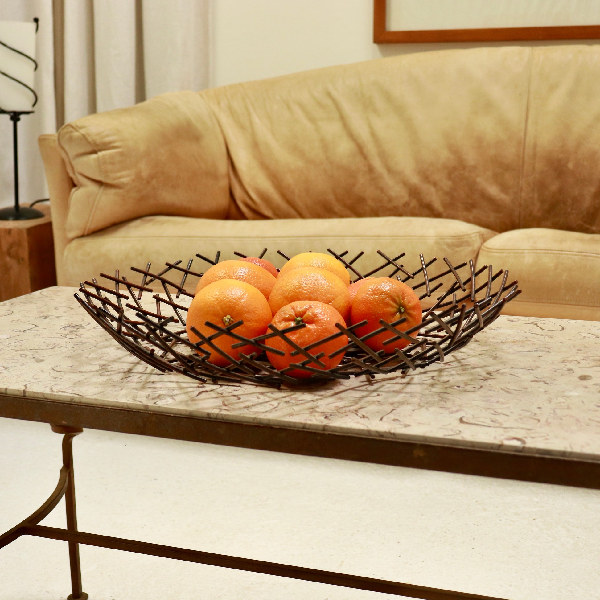 “Patinated metal fruit bowl with crossed rod construction”