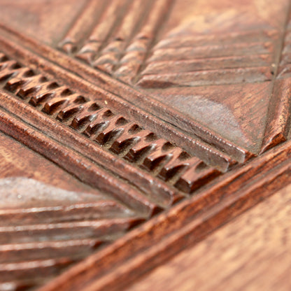 Close-up of notched borders and angular chip carving on the hardwood tabletop.