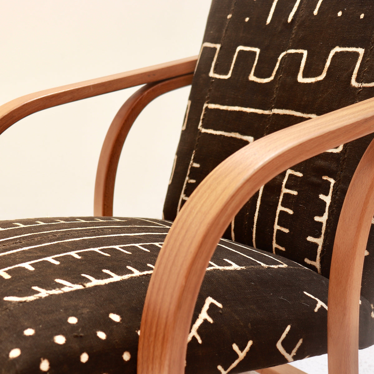 Antique Malian mud cloth detail showing textured cotton weave, a stitched strip join and cream branching motifs on a dark ground.