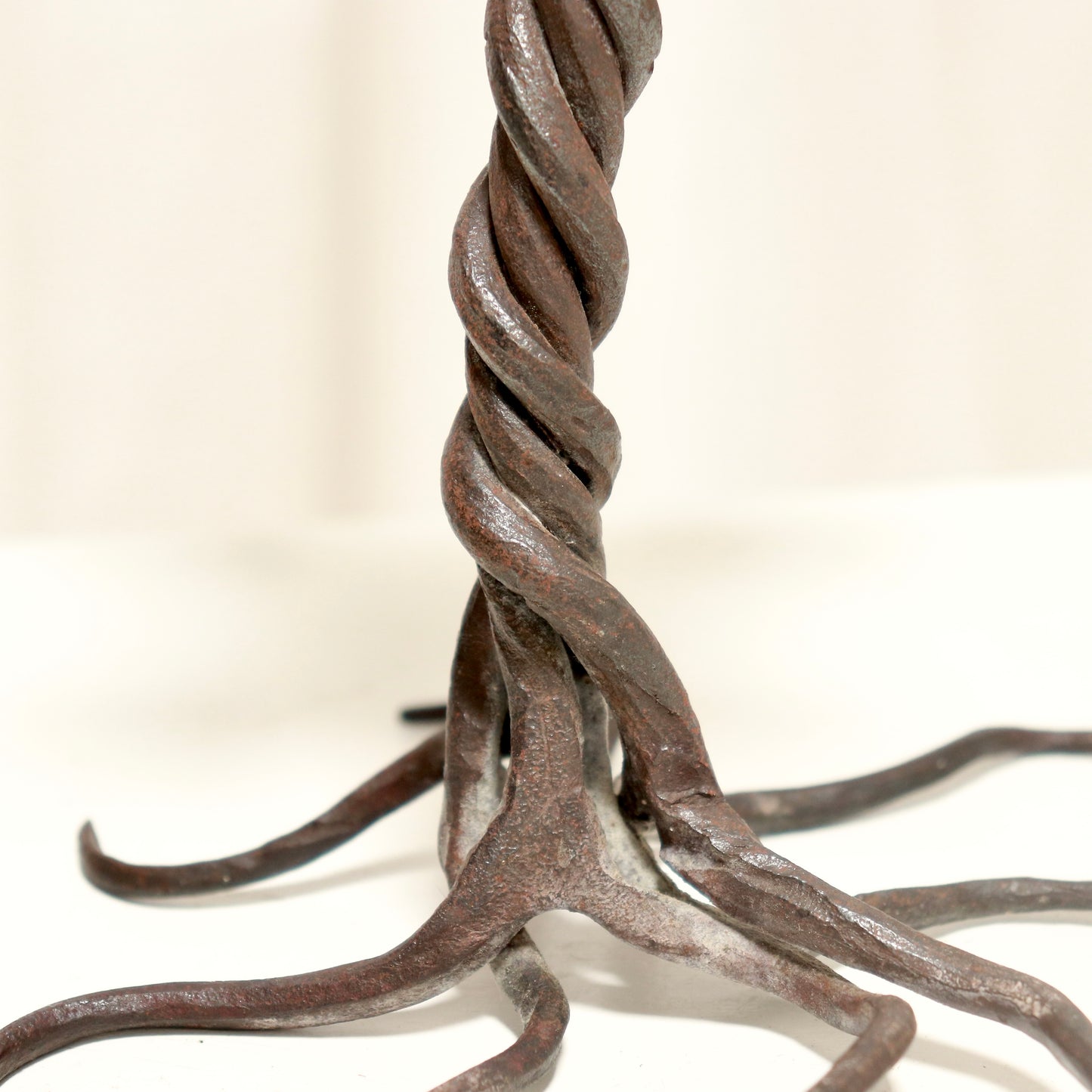 “Detail of twisted iron stem and root-like feet on candlestick”