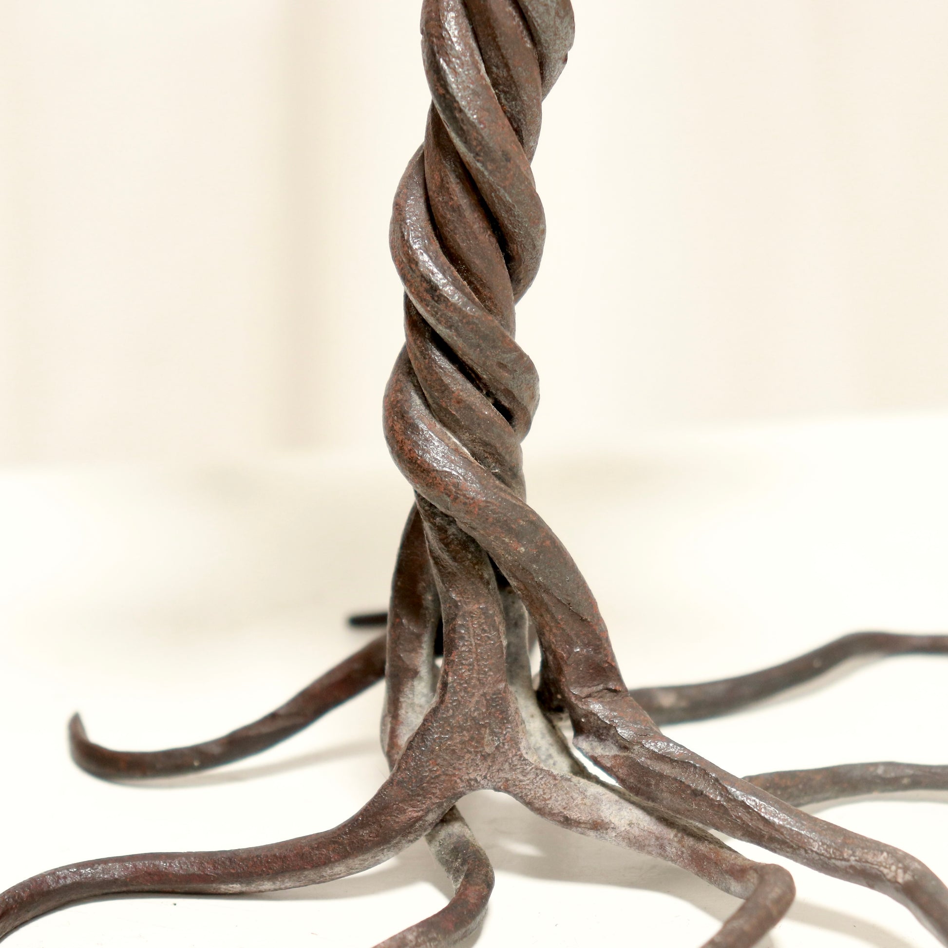 “Detail of twisted iron stem and root-like feet on candlestick”