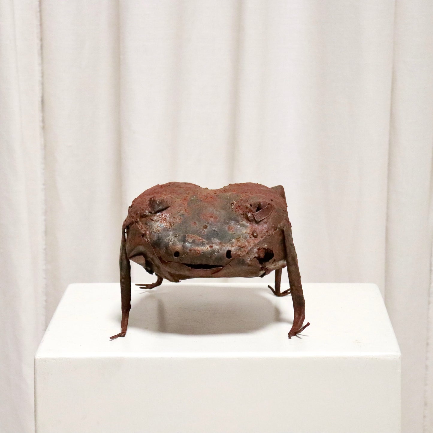 Front view of rusted metal frog with slit smile.