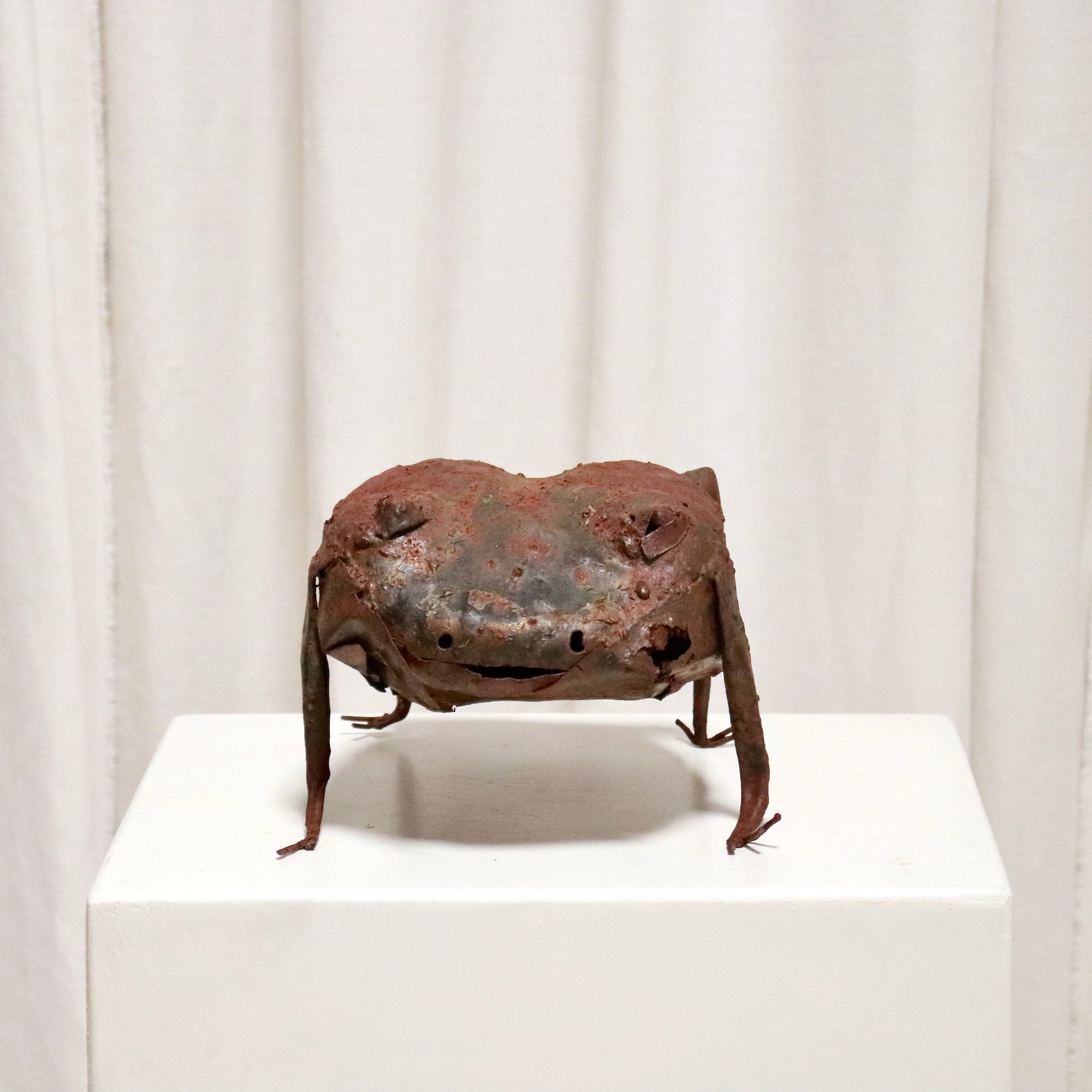 Front view of rusted metal frog with slit smile.