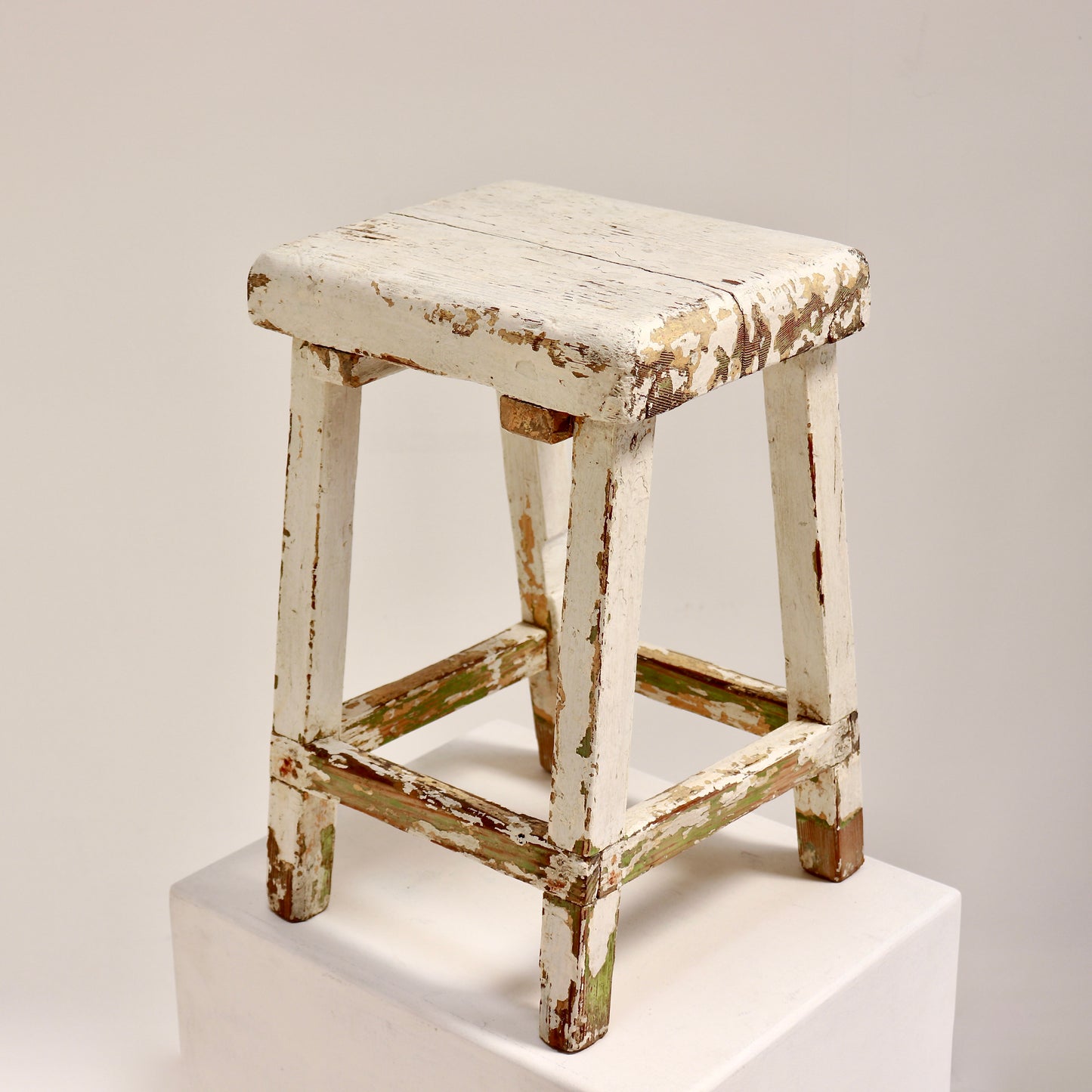 Vintage wooden stool with chippy white paint and rustic patina