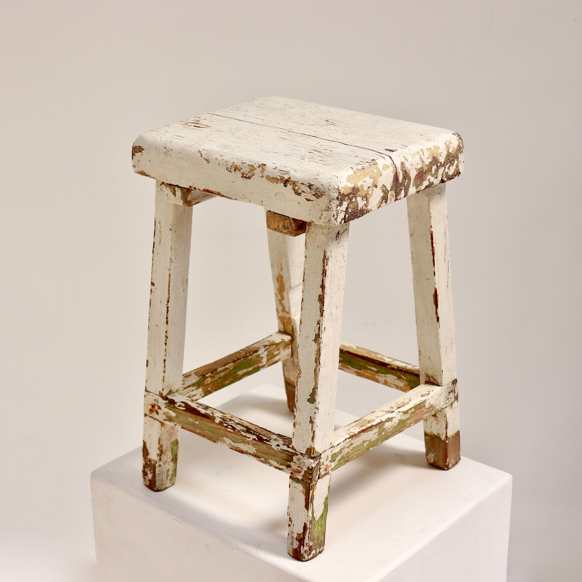 Vintage wooden stool with chippy white paint and rustic patina