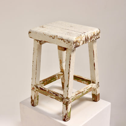 Vintage wooden stool with chippy white paint and rustic patina
