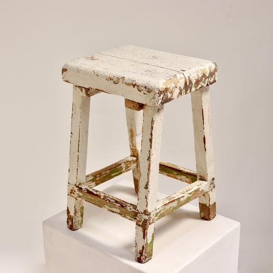 Vintage wooden stool with chippy white paint and rustic patina