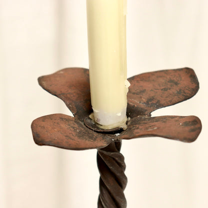 “Petal-shaped drip tray on rustic wrought iron candle holder”