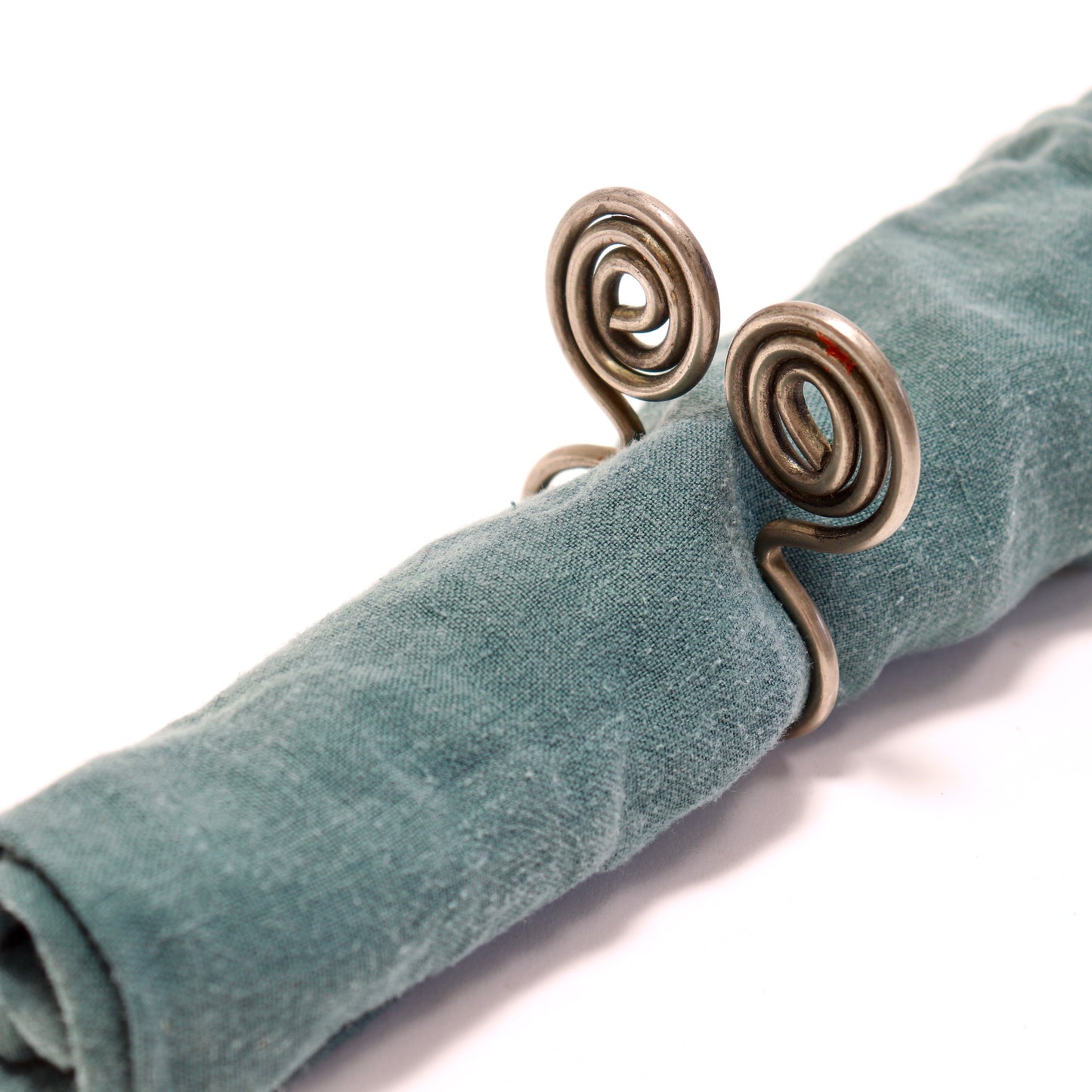 Sculptural metal napkin ring holding linen napkin.