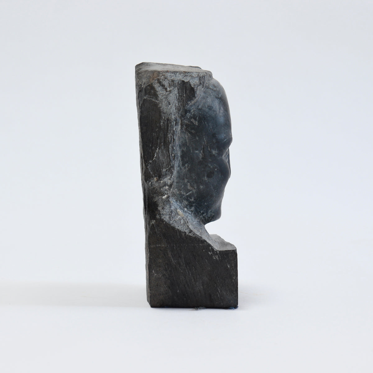 Side profile of the slate bust showing the shallow portrait carving and thickness of the stone block