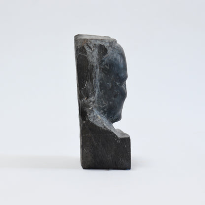 Side profile of the slate bust showing the shallow portrait carving and thickness of the stone block