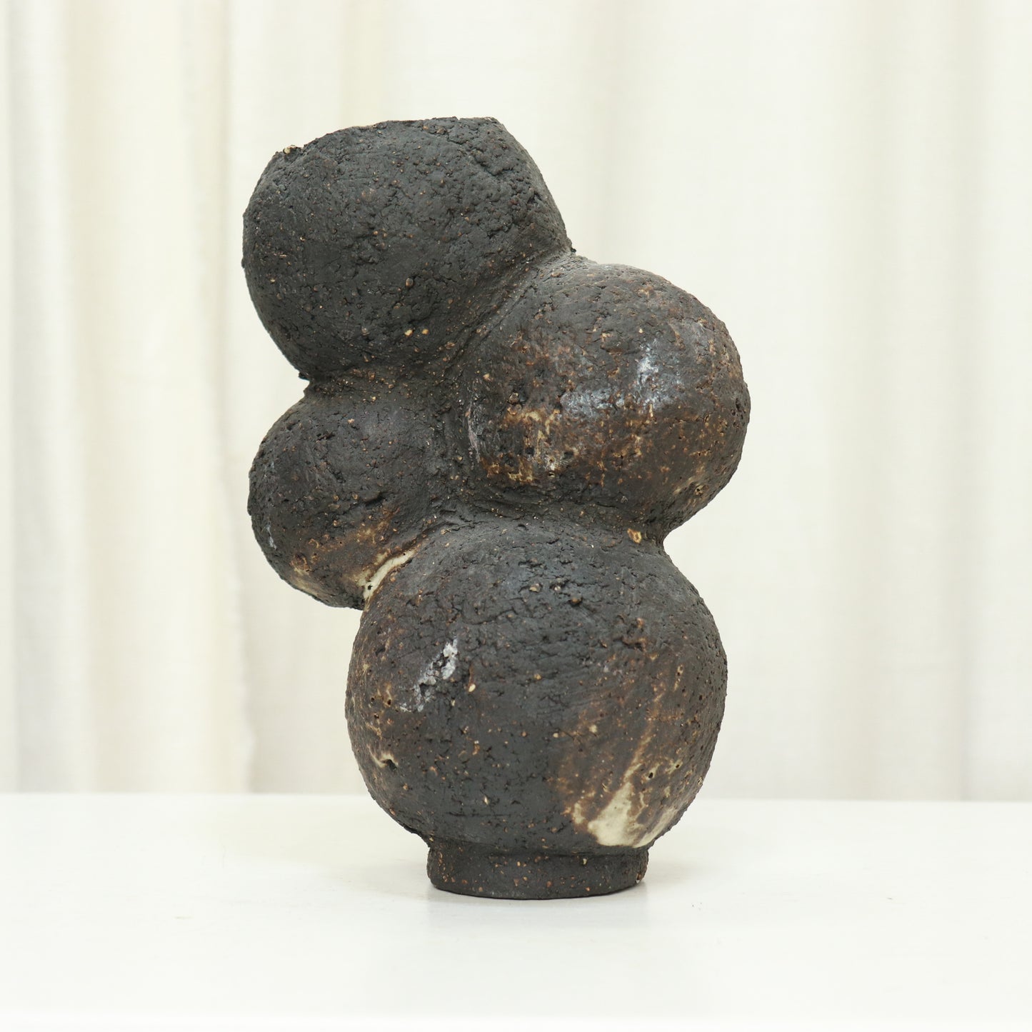 Organic bulbous studio ceramic vase with textured black surface