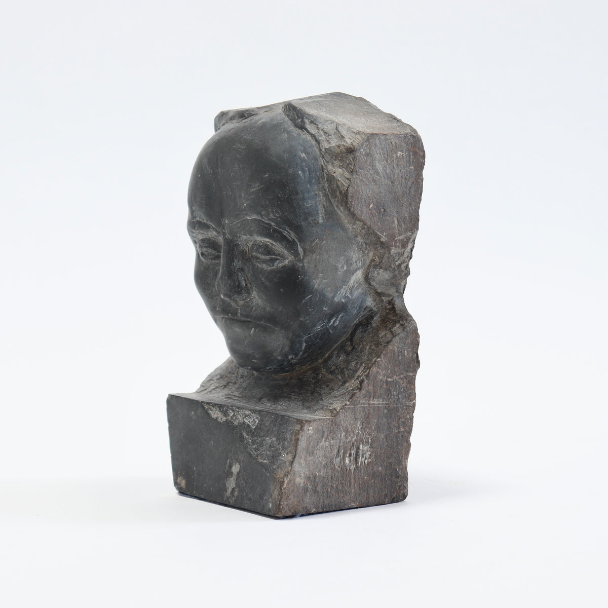 Angled view of the slate portrait showing the smooth forehead and cheeks against fractured stone.