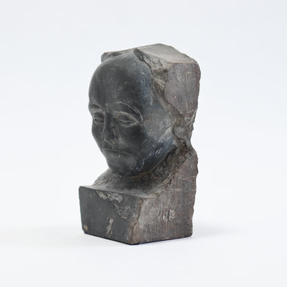 Angled view of the slate portrait showing the smooth forehead and cheeks against fractured stone.