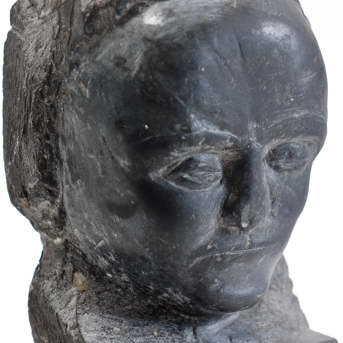 Close-up of the carved eyes, nose and mouth, with fine tool marks and surface scratches.