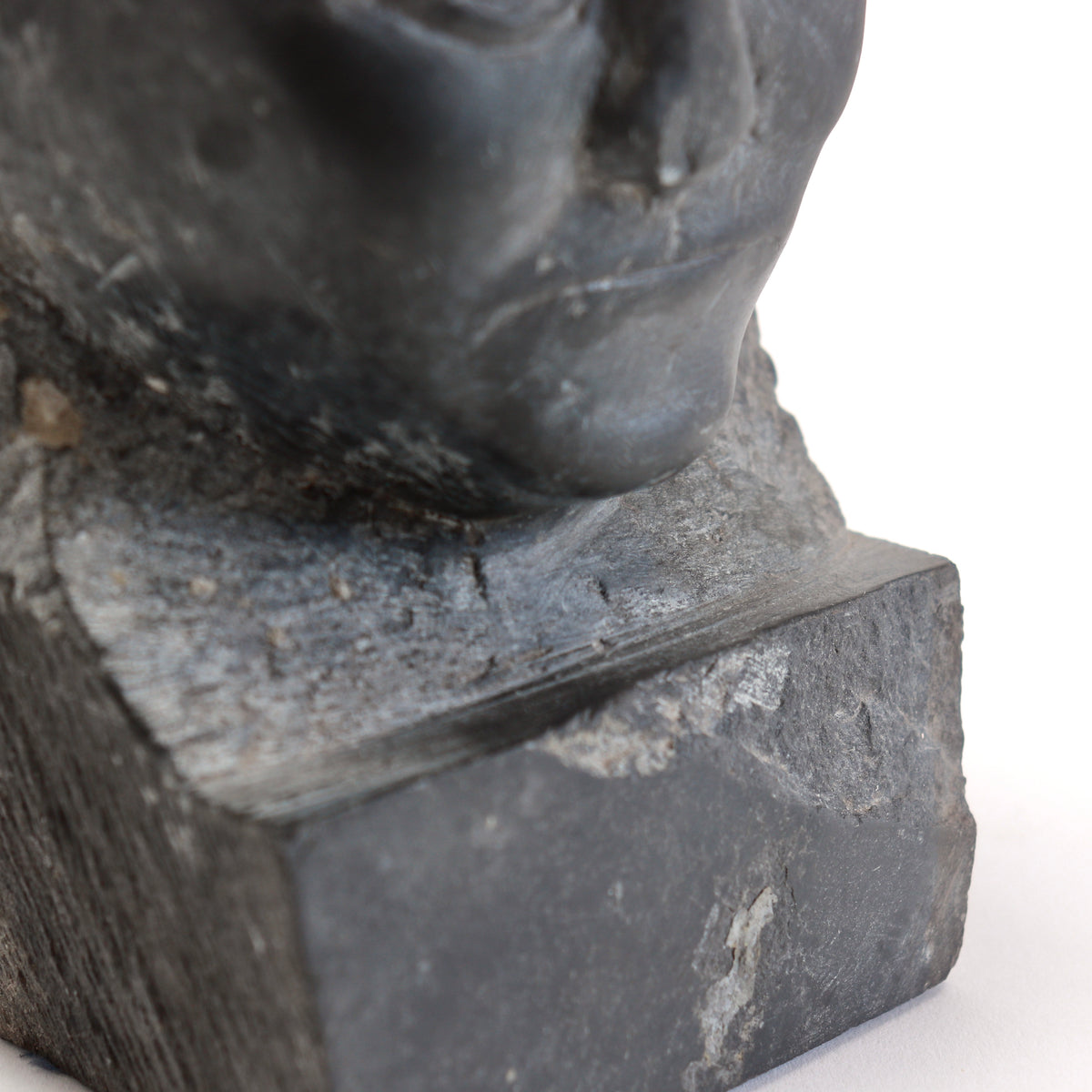 Detail of the chin, roughly carved neck and chipped front edge of the integral slate base.