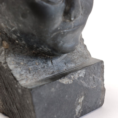 Detail of the chin, roughly carved neck and chipped front edge of the integral slate base.