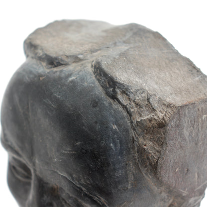 Detail of the rounded forehead meeting the rough, layered stone at the top of the bust.