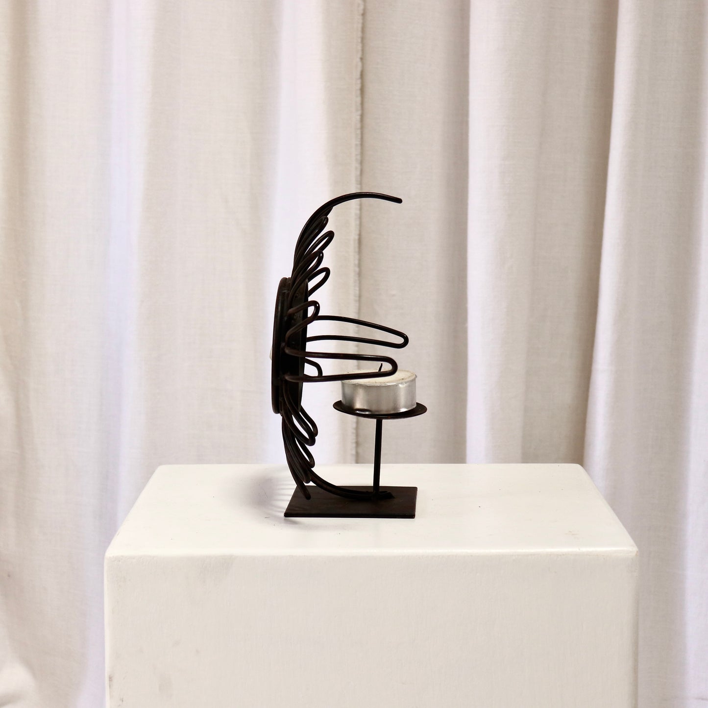 Side angle of iron sunburst frame with tealight saucer.