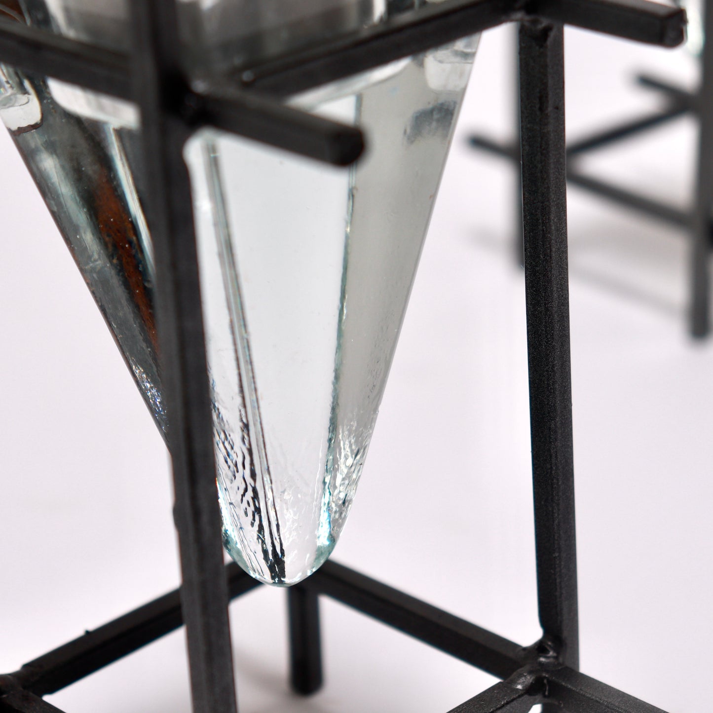 Detail of blackened steel frame and moulded glass prism candle holder
