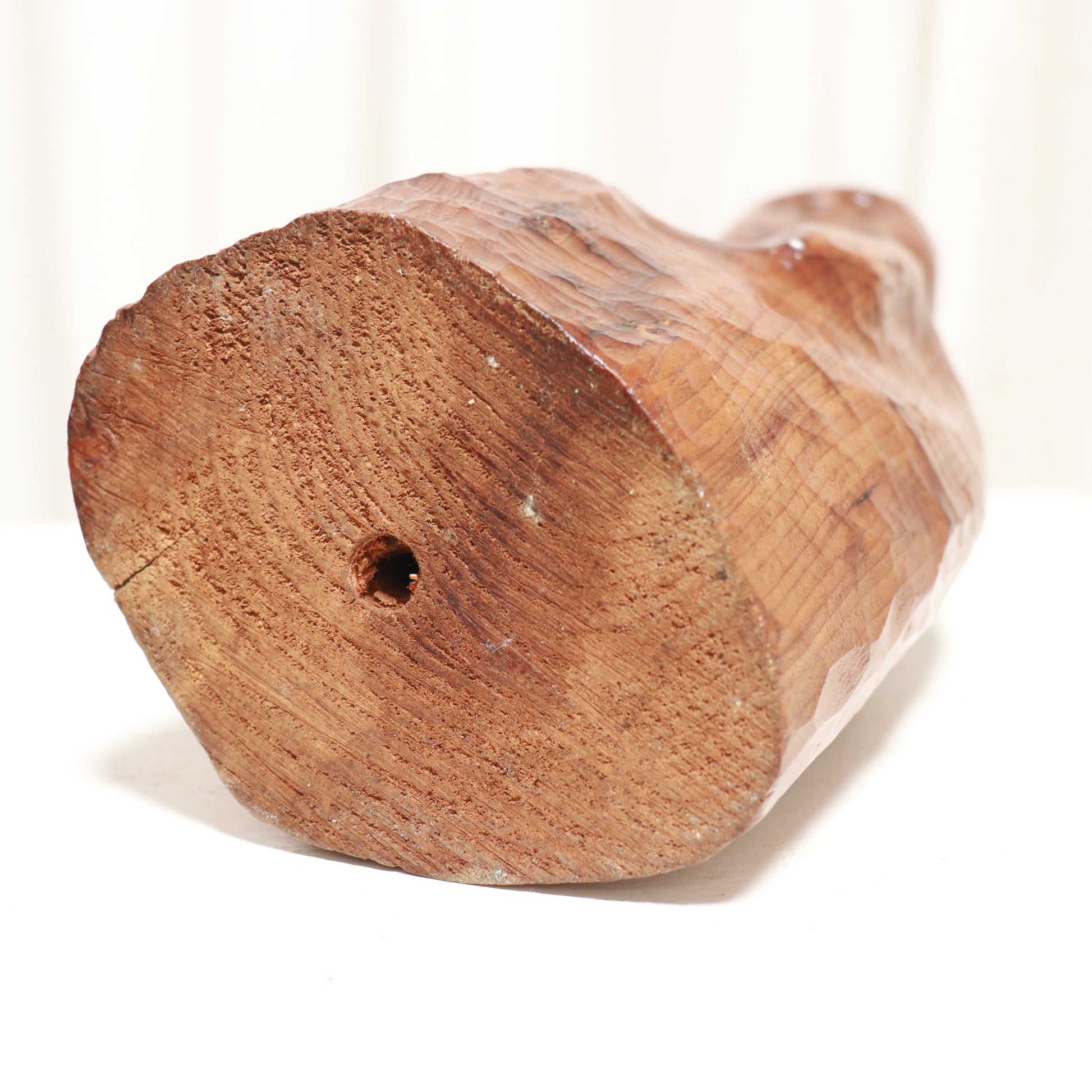 “Underside and base of vintage carved wooden figure showing tool marks”