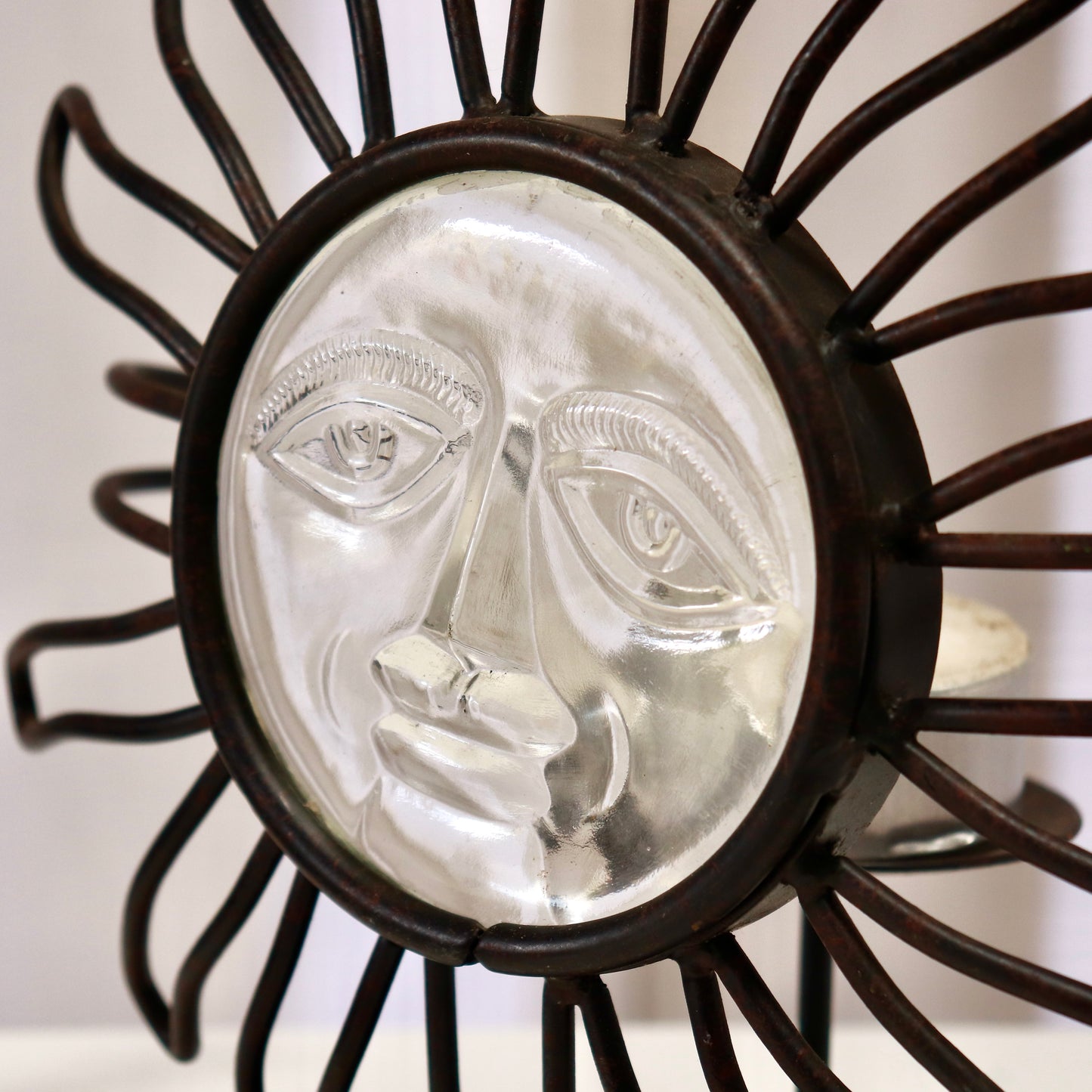 Close-up of pressed-glass sun face in iron bezel.