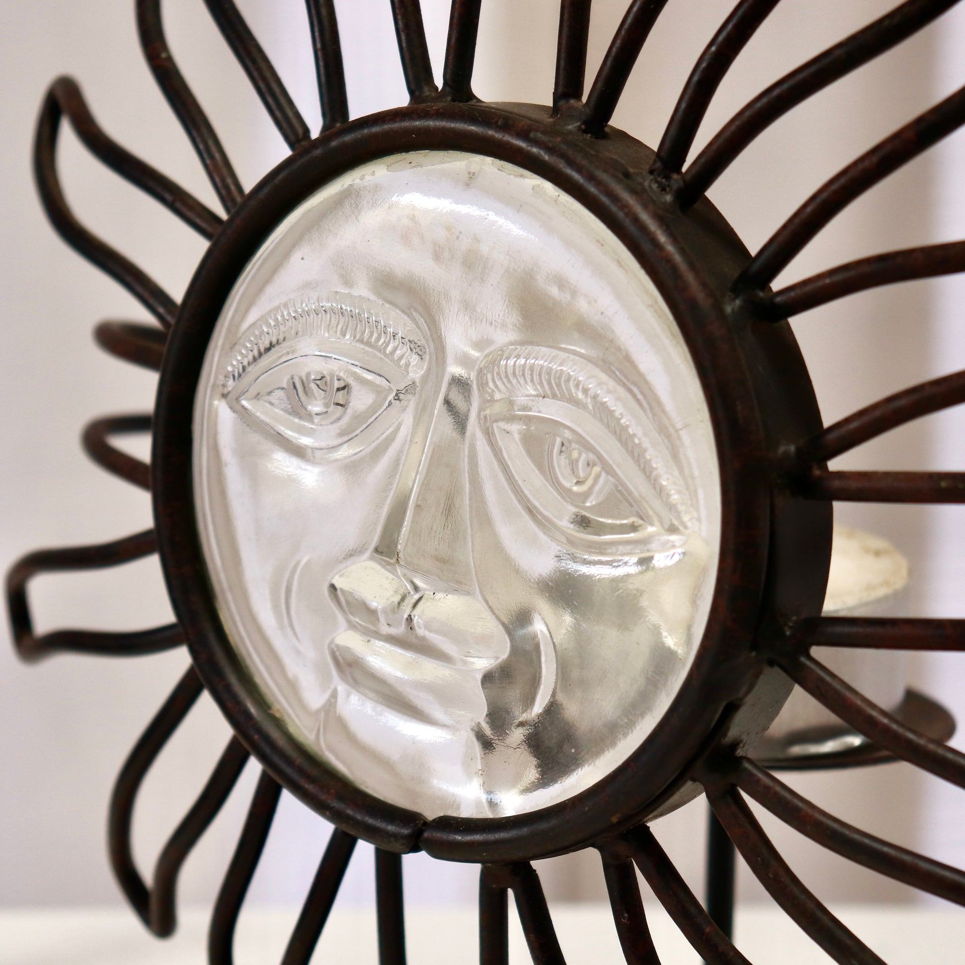 Close-up of pressed-glass sun face in iron bezel.