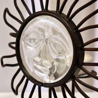 Close-up of pressed-glass sun face in iron bezel.