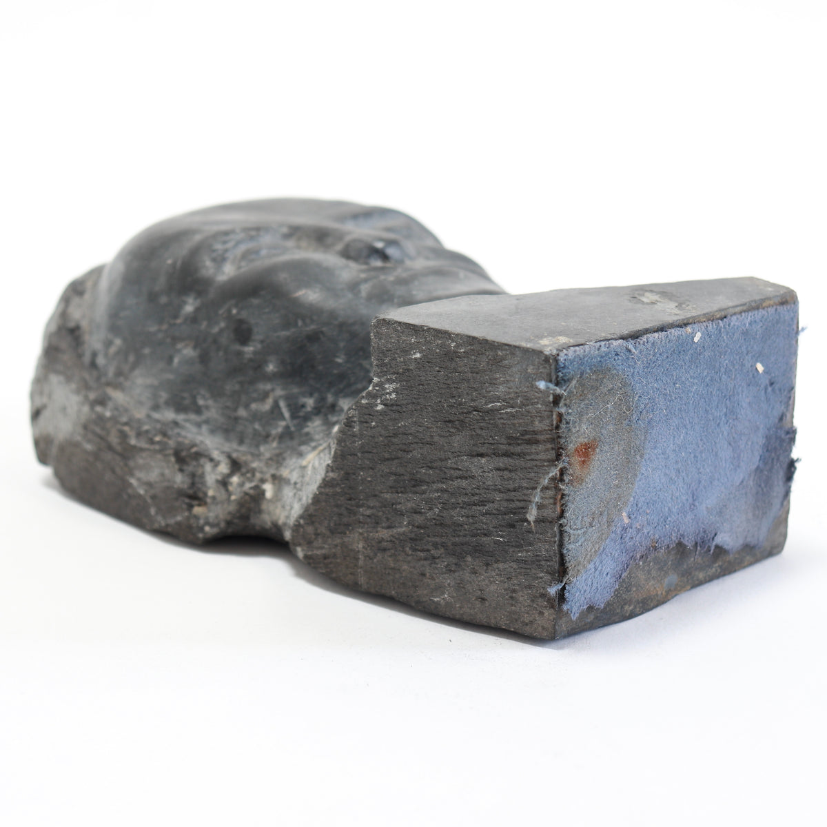 Underside of the slate bust showing remnants of blue fabric attached to the base.